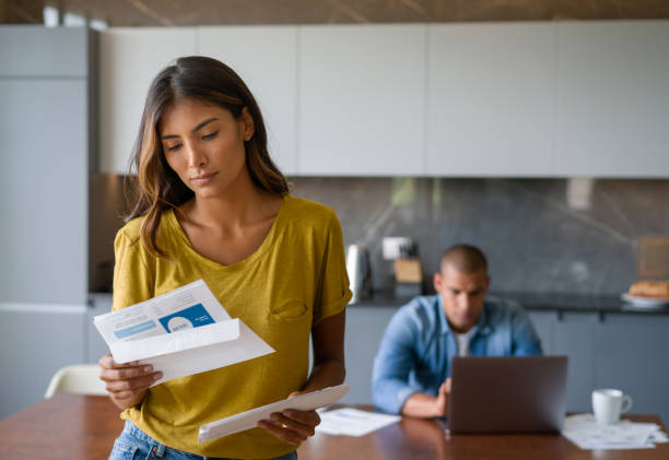 woman at home looking worried getting bills in the mail - opening mail letter envelope imagens e fotografias de stock