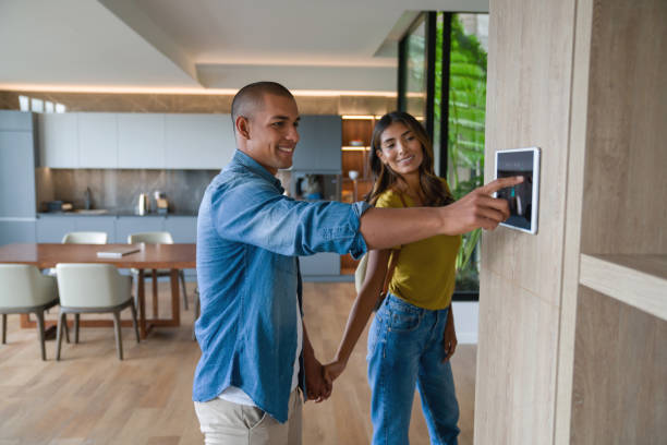 couple verrouillant la porte de leur maison à l’aide d’un système domotique - security system security burglar alarm home interior photos et images de collection