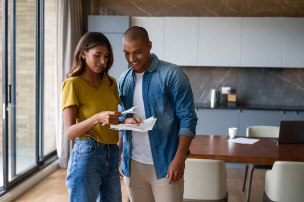 happy couple at home reading a letter in the mail - opening mail letter envelope imagens e fotografias de stock