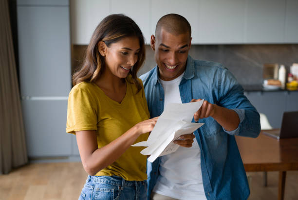 excited couple getting good news in the mail - opening mail letter envelope imagens e fotografias de stock