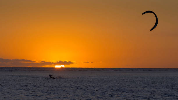 istock Man kitesurfing at sunset during a beautiful orange sunset 1338101434