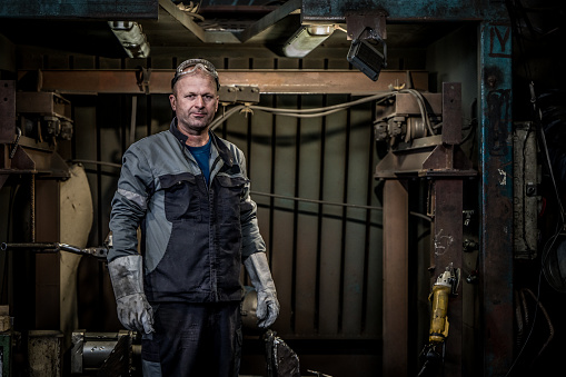Portrait of mature worker standing in steel mill.