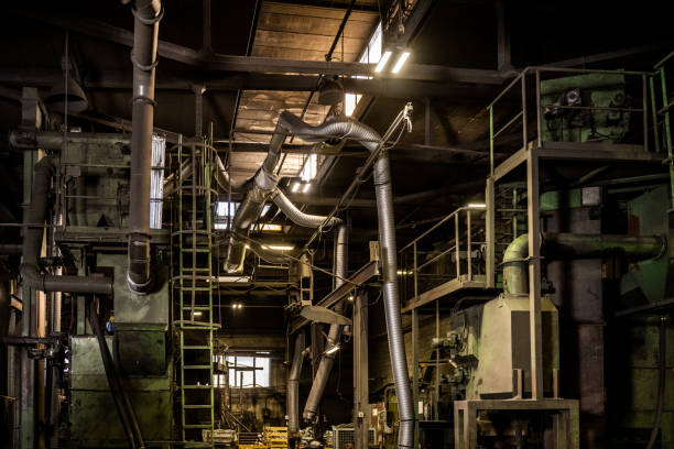 Interior view of steel mill with pipes and ladder.