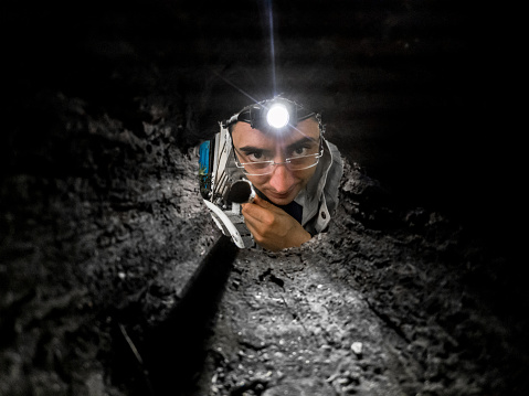 Man with a head torch Looking Inside a Hole