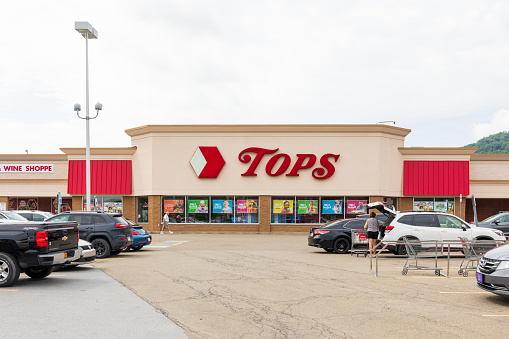 Bradford, PA, USA-13 August 2021: A TOPS Market.  These grocery stores are located in New York, Pennsylvania and Vermont.  Shows store front, parking lot and two people.