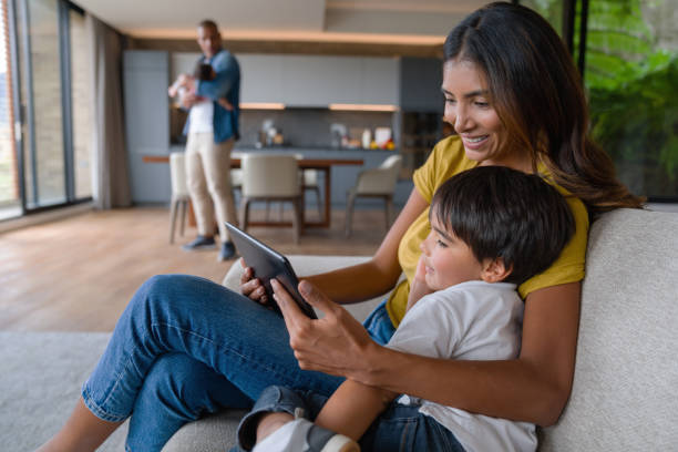 istock Happy boy playing on a tablet with his mother next to him 1338106312