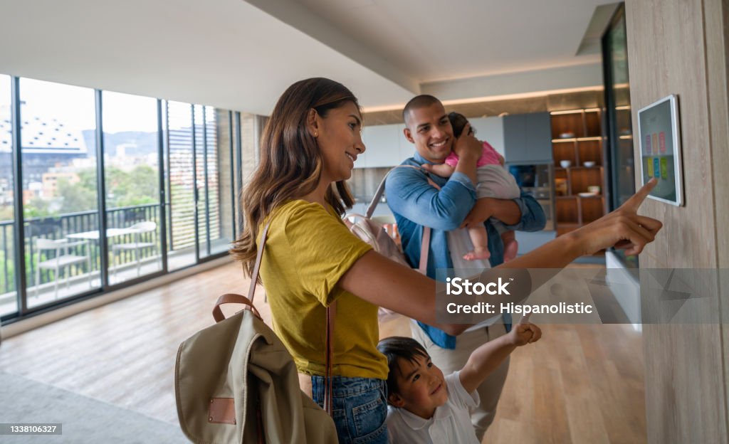 Happy family leaving the house locking the door using automated security system Happy Latin American family leaving the house locking the door using automated security system - smart home concepts. **DESIGN ON SCREEN BELONGS TO US** Home Automation Stock Photo