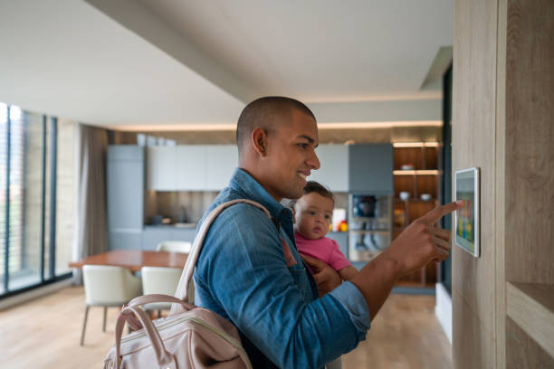 Man leaving the house with his baby and locking the door using a home automation system Happy Latin American man leaving the house with his baby and locking the door using a home automation system â smart home concepts burglar alarm stock pictures, royalty-free photos & images