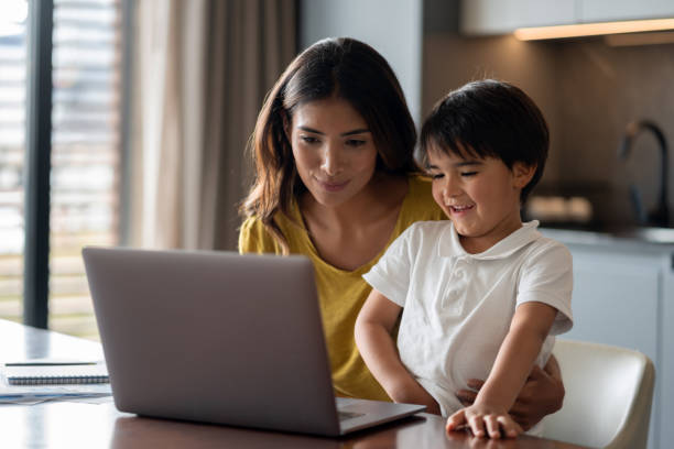 istock Mother and son watching videos at home on a laptop computer 1338106339