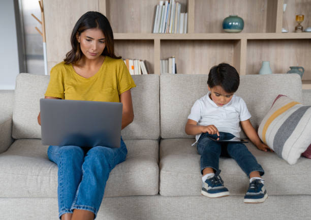 istock Boy watching videos on a tablet while his mother is busy on her laptop 1338106349