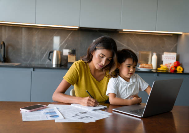 istock Boy watching videos on a laptop while his mother tries to work 1338106351