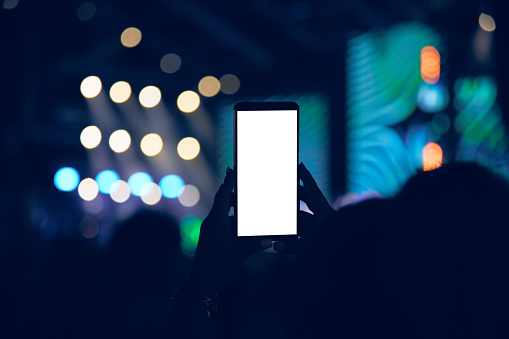 Person holding modern smartphone on a concert.