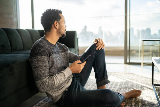 istock Man holding smartphone and looking away at home 1338107084