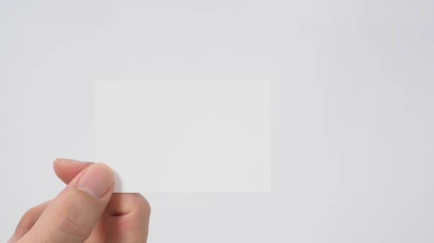 istock Close up of hand holding empty small card on white background. 1338108803