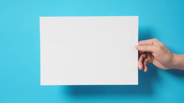 istock Hand is holding the A4 paper board on blue background. 1338109984