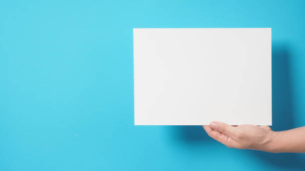 istock Hand is holding the A4 paper on blue background. 1338109985