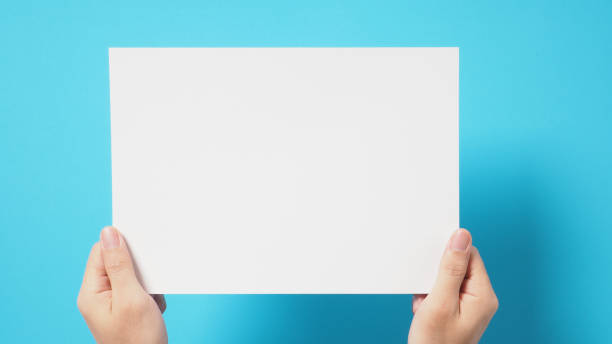 istock Hand is holding the A4 paper board on blue background. 1338110004