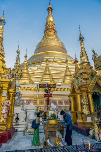 myanmar. yangon. coppia che fa un'offerta a shwedagon pagoda - shwedagon pagoda immagine foto e immagini stock