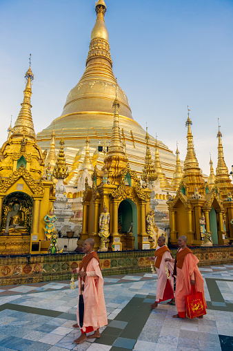 Myanmar. Yangon. Nuns walking in front of the great golden stupa at Shwedagon Pagoda.  Buddhist holy place is the first religious center of Burma