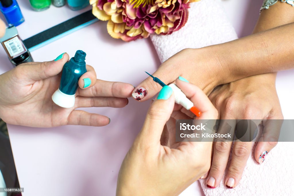 Woman getting a manicure and nail painting in the foreground Flower Stock Photo