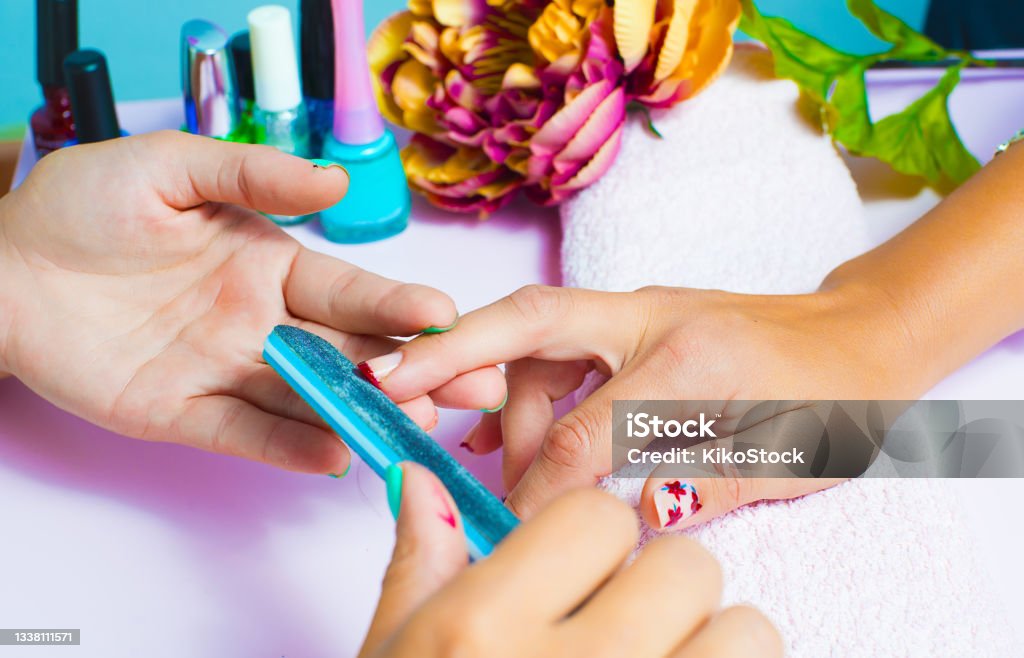 Woman getting a manicure and nail painting in the foreground Acrylic Painting Stock Photo