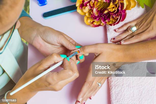 Woman Getting A Manicure And Nail Painting In The Foreground Stock Photo - Download Image Now