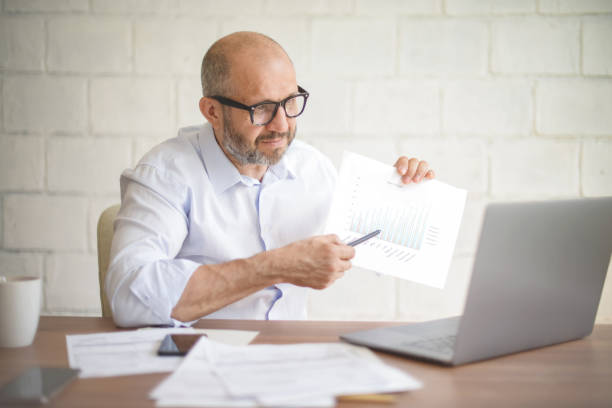 istock mature adult man working from office ( with laptop,paperwork, video conference) 1338114291