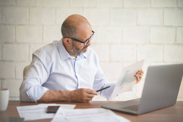 istock mature adult man working from office ( with laptop,paperwork, video conference) 1338114855