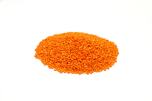 Raw red lentils seeds heap on white background. Food ingredient. Top view.