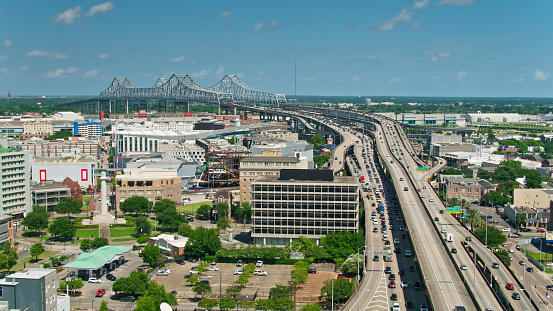 Aerial view of New Orleans on a sunny day in summer, looking over the Warehouse District towards the Mississippi River and the Crescent City Connection Bridge.