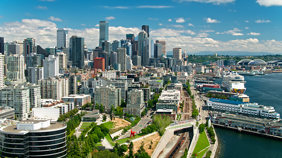 Aerial shot of Seattle, Washington on a sunny day in summer from over Lower Queen Anne, also referred to as Uptown, looking Downtown along the waterfront as a freight train passes through.
