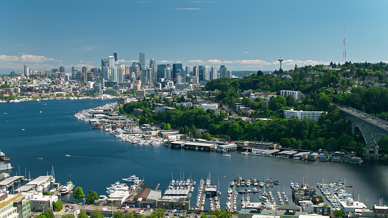 Aerial shot of Seattle, Washington on a sunny day in summer, looking along the Aurora Bridge from the Fremont bank of Lake Union towards East Queen Anne and Eastlake, with the downtown skyline in the distance and, much further away, the snowcap of Mount Rainier.