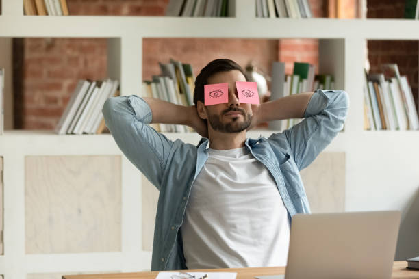 istock Employee relaxing at workplace with sticky notes on his eyes 1338118940