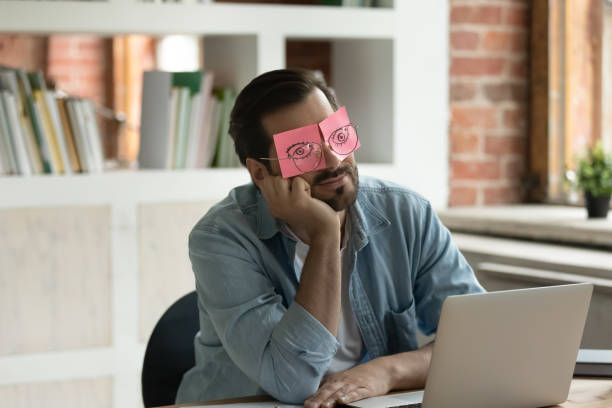 istock Sleeping employee hides eyes under sticky notes seated at desk 1338118942
