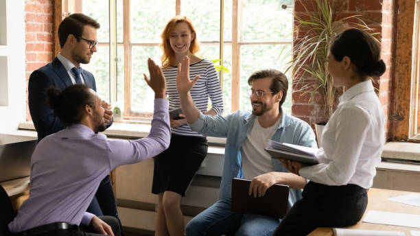 Multiracial employees giving high five during group briefing in office African and Caucasian workmates diverse buddies friends giving high five gesture making agreement during group briefing in office. Make a bet or wager, partnership, support, racial equality concept office buddies stock pictures, royalty-free photos & images