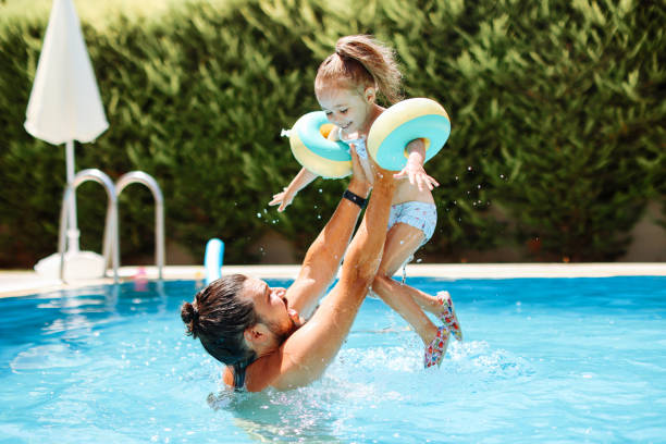 bambina carina che si diverte con i genitori in piscina - arm band foto e immagini stock