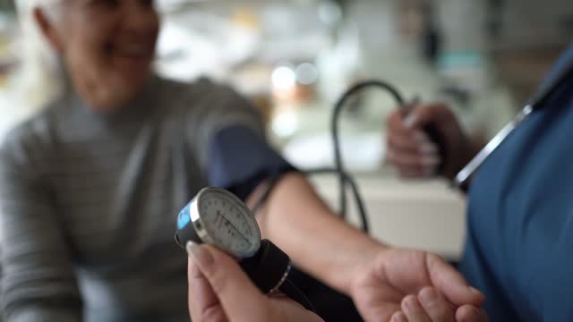 Nurse taking blood pressure of a senior patient at home