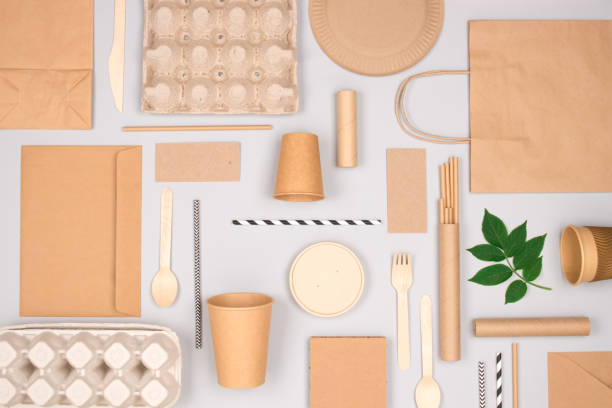 istock Different eco-friendly tableware and kraft paper food packaging on gray background. Street food paper packaging - cups, plates, straws, containers and paper bags. Mockup, flat lay. Selective focus 1338134288