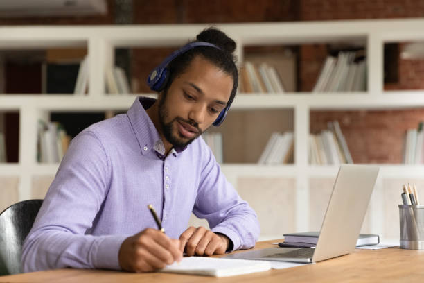 el e-learning del hombre africano se prepara para los exámenes utiliza el curso de audio en línea - digital enhancement audio fotografías e imágenes de stock