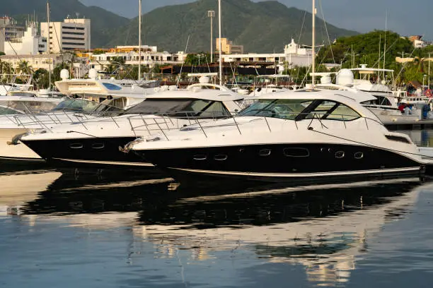 Luxury motorboats and sailboats Docked at a Marina on mountains background.