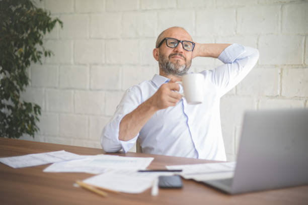 istock mature adult man working from office ( with laptop, paperwork, coffee) 1338136117