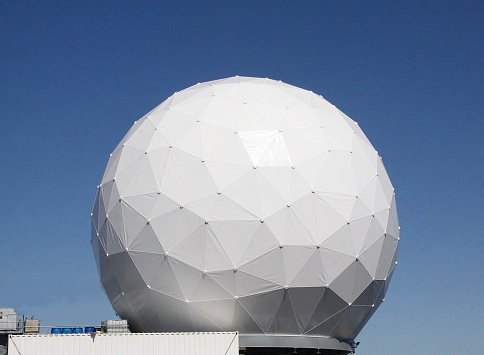 Large radar dome sitting on a ship with a perfect spherical shape