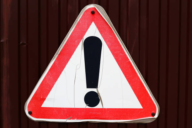 istock Old sign with peeling paint on a metal fence: an exclamation point in a triangle indicating other dangers 1338145251