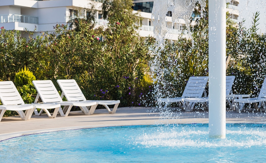 Sun loungers stand by the pool with a children's waterfall fountain.