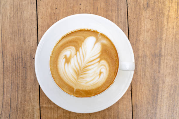 Top view of Latte coffee or cappuccino coffee in white cup with beautiful tree latte art on wooden table.
