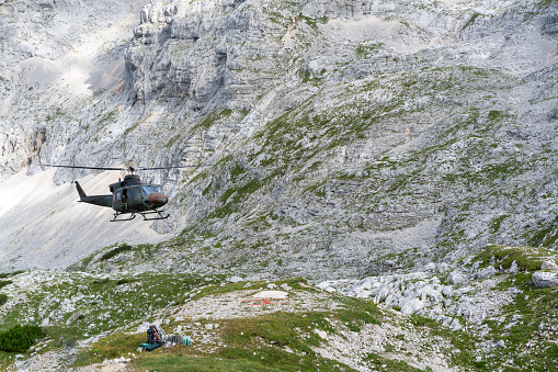 Rescue helicopter flying against high rocky mountain in Julian Alps, Slovenia.