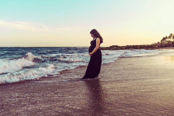 istock Pregnant woman on a tranquil sunset beach 1338177685