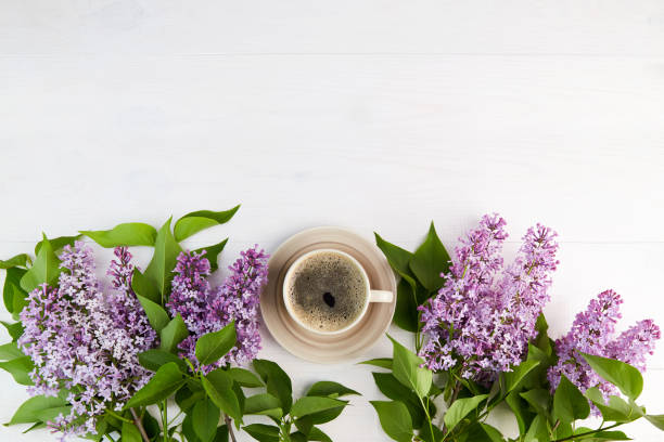 istock Spring background. Lilac branches and cup of coffee on a white wooden background. 1338180956