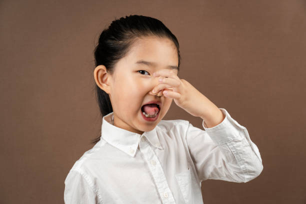 Little Girl Pinching Nose on Brown Background Little Girl Pinching ​Nose ​on Brown Backgroud disgust stock pictures, royalty-free photos & images