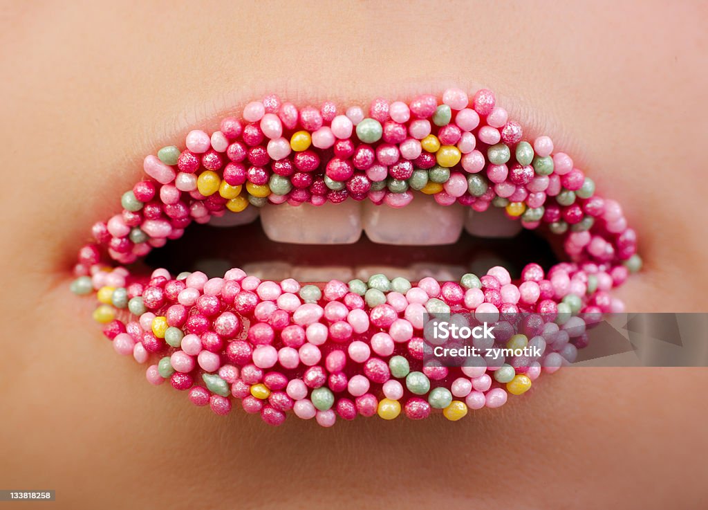 Sweet Candy Lips A young female model has lip gloss and cake decorations on her lips to make her more attractive. Human Lips Stock Photo